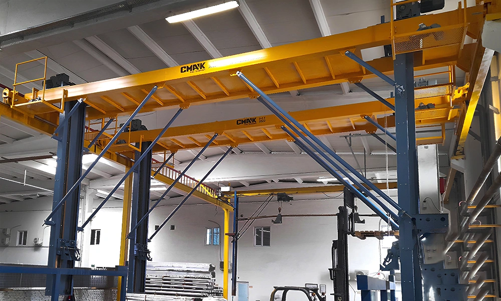 A heavy-duty automated processing system from the special cranes CMAK line, custom-built with dual yellow overhead girders and rigid vertical lifting masts for an industrial aluminum anodizing facility.