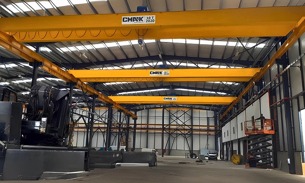 A row of three yellow 10-ton CMAK single-girder bridge cranes installed consecutively in a spacious industrial manufacturing workshop.