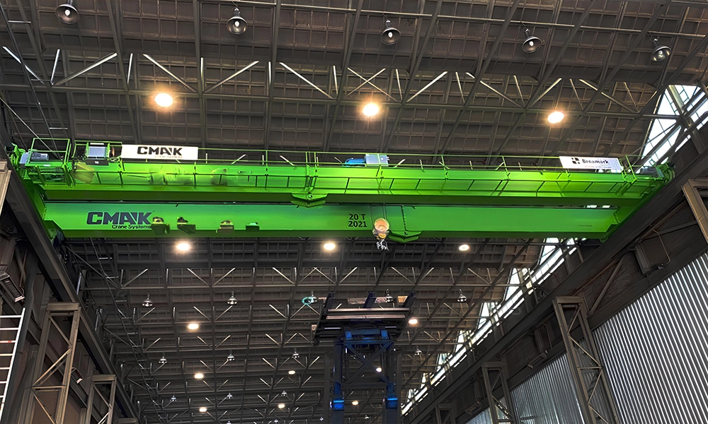 A custom lime green 20-ton CMAK double-girder bridge crane featuring a full-length maintenance walkway platform installed inside a heavy industrial manufacturing facility.