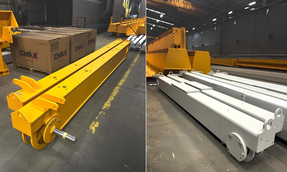 Industrial manufacturing floor showcasing heavy-duty end truck carriages CMAK painted in bright yellow and primer gray, ready for overhead crane bridge assembly.