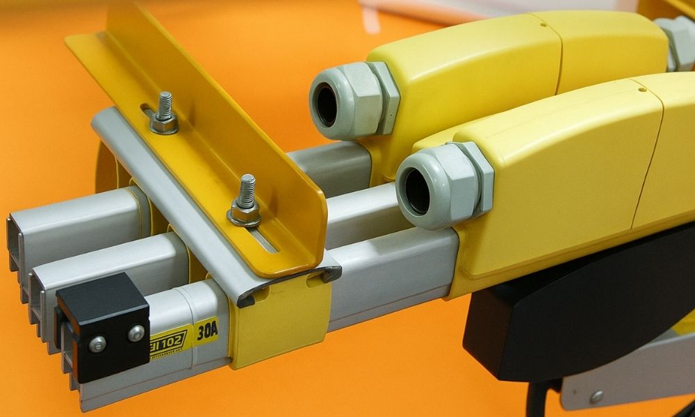 Close-up of yellow terminal power feed connection boxes with cable entry glands mounted onto PVC enclosed busbar systems, showcasing the 40A current rating label and tracking brackets.